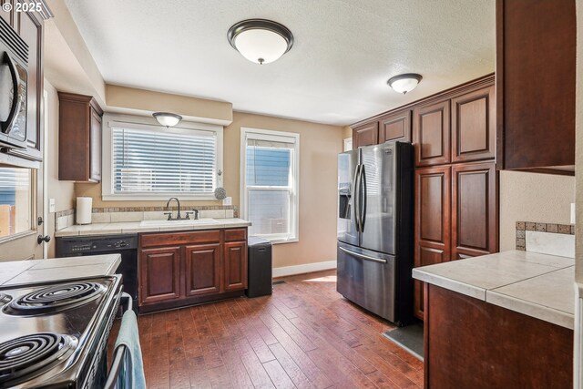 kitchen with stainless steel appliances, baseboards, a sink, and dark wood-type flooring