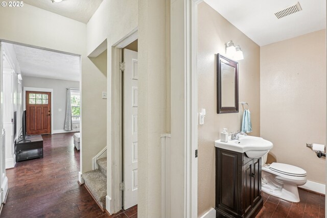 bathroom with visible vents, baseboards, toilet, and hardwood / wood-style flooring