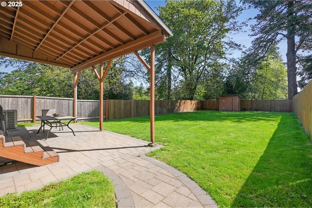 view of yard featuring a storage unit, a fenced backyard, an outbuilding, a patio area, and central air condition unit