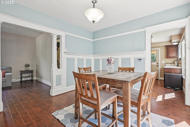 dining space with decorative columns and dark wood finished floors