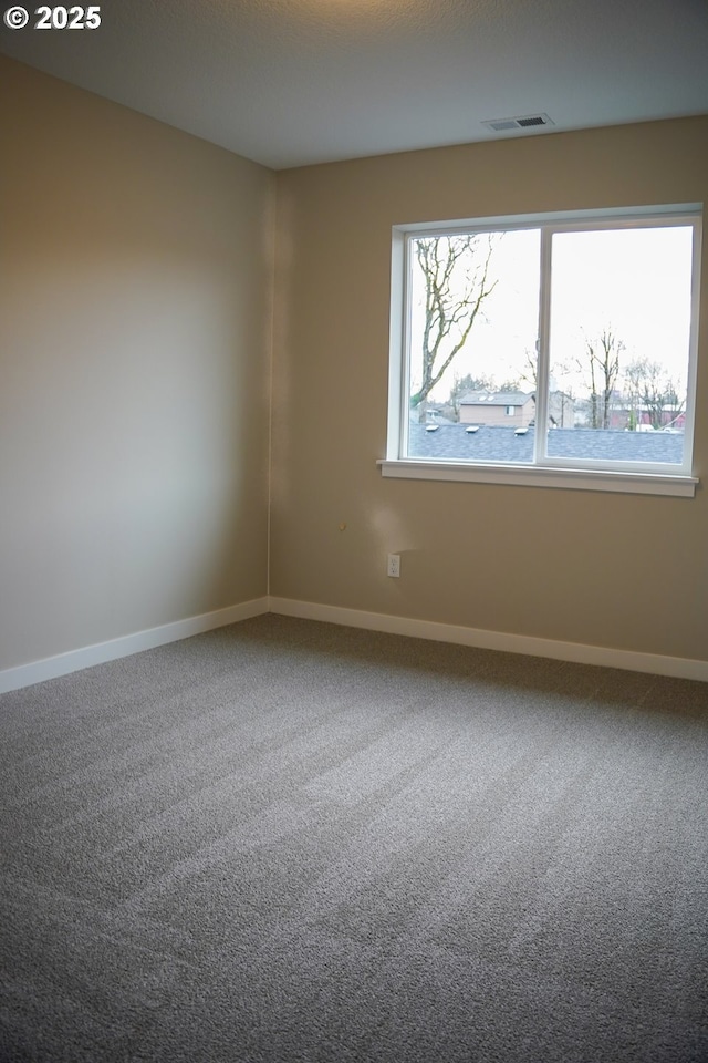 carpeted spare room featuring visible vents and baseboards