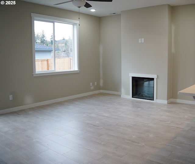 unfurnished living room featuring baseboards, a glass covered fireplace, ceiling fan, wood finished floors, and recessed lighting