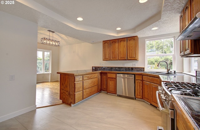 kitchen with stainless steel appliances, brown cabinets, ventilation hood, a peninsula, and a textured ceiling