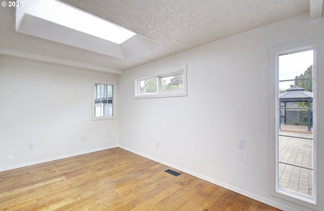 unfurnished room with baseboards, light wood-style flooring, and a textured ceiling