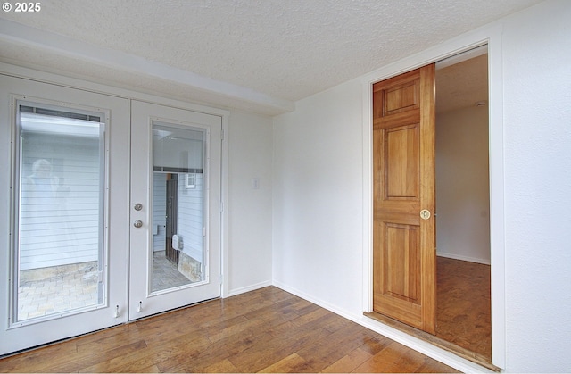 empty room with a textured ceiling, dark wood finished floors, and baseboards