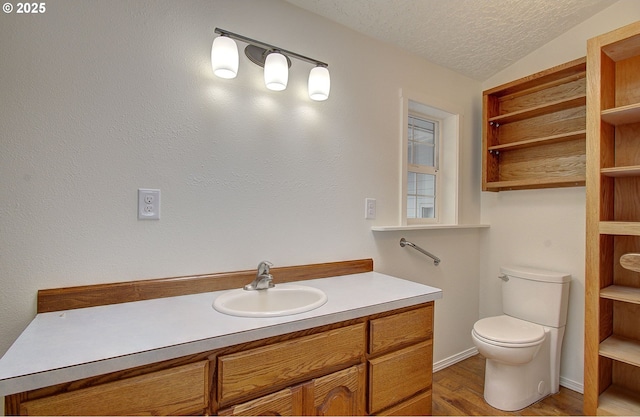 bathroom with a textured ceiling, toilet, wood finished floors, and vanity