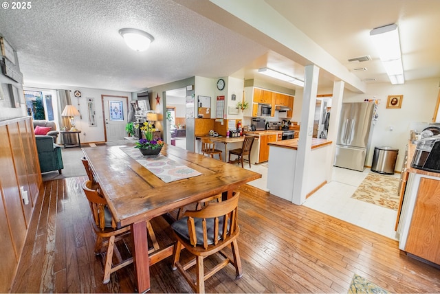 dining room with light hardwood / wood-style flooring and a textured ceiling