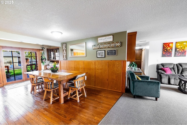 dining room featuring hardwood / wood-style flooring, wooden walls, and a textured ceiling