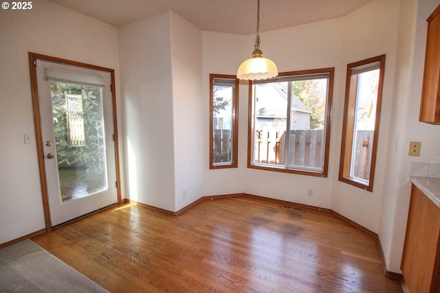 unfurnished dining area with baseboards and wood finished floors