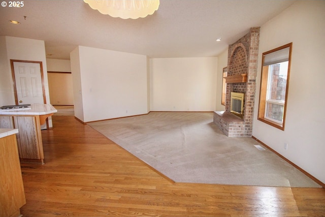 unfurnished living room with visible vents, recessed lighting, a fireplace, light wood finished floors, and baseboards