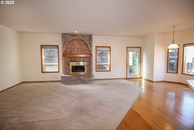 unfurnished living room with baseboards, wood finished floors, and a fireplace