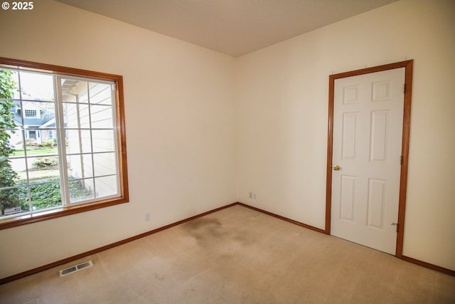 empty room with visible vents, baseboards, and light colored carpet