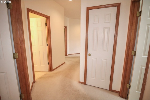 hallway featuring baseboards and light carpet