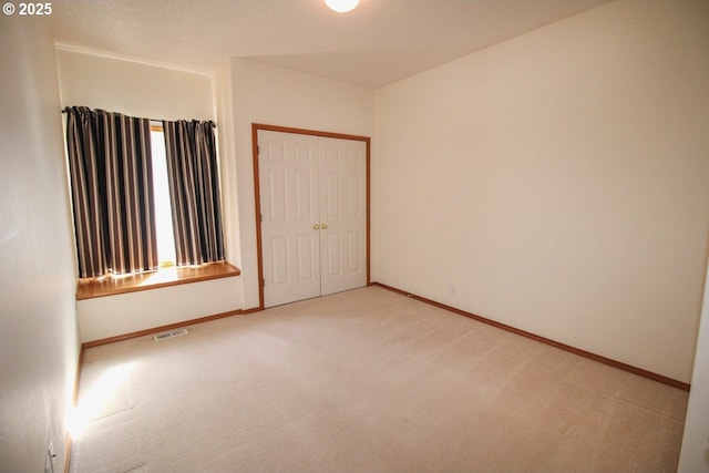 carpeted spare room with visible vents and baseboards