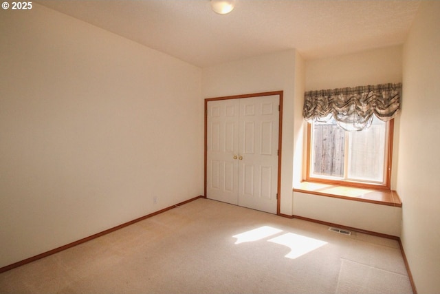 carpeted spare room featuring visible vents and baseboards