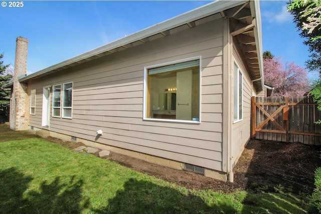 view of side of home with a lawn, fence, and crawl space