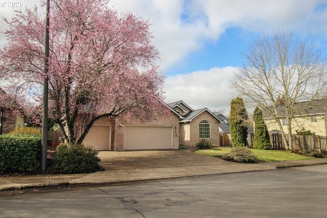 view of front of home featuring brick siding, fence, a garage, and driveway