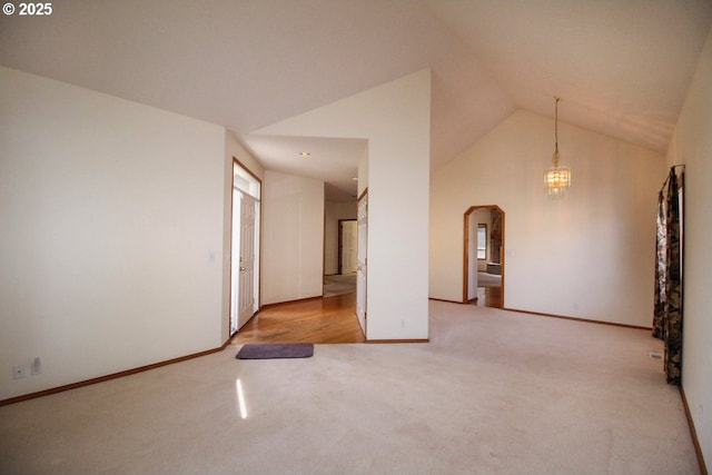 spare room featuring arched walkways, a notable chandelier, carpet floors, and high vaulted ceiling