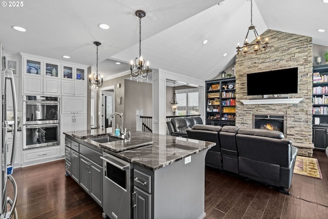 kitchen featuring a sink, a chandelier, appliances with stainless steel finishes, dark wood finished floors, and lofted ceiling