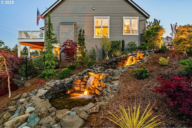 rear view of house featuring a garden pond and a balcony