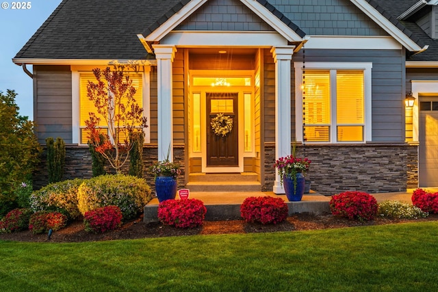 view of exterior entry with stone siding and a lawn