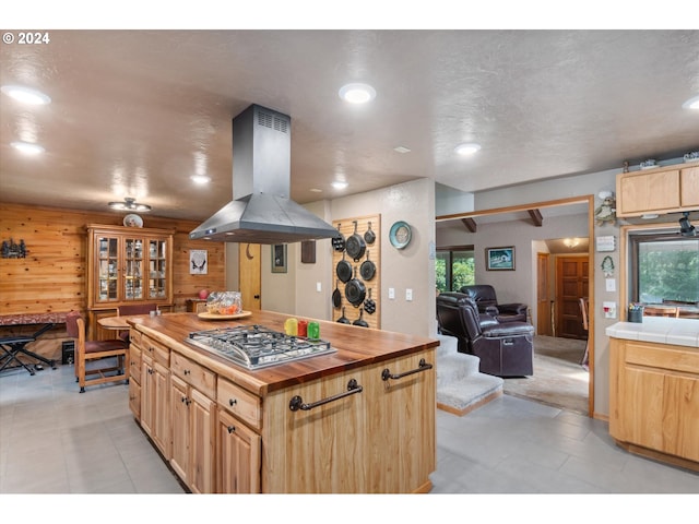 kitchen with wood walls, light brown cabinetry, recessed lighting, island exhaust hood, and stainless steel gas stovetop