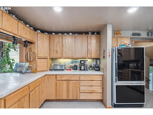 kitchen featuring recessed lighting, refrigerator, light tile patterned flooring, and tile counters