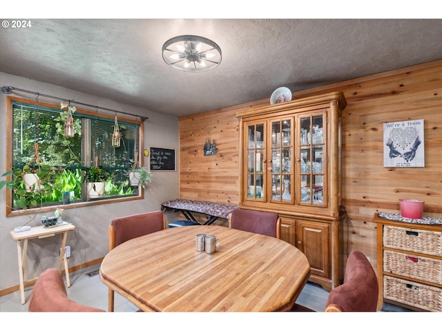 dining area featuring wooden walls and a textured ceiling