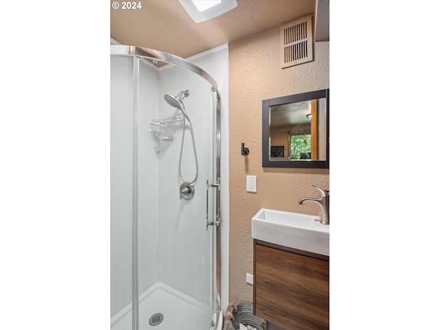 bathroom with a textured wall, visible vents, a shower stall, and vanity