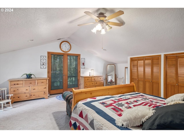 bedroom with carpet flooring, a textured ceiling, access to exterior, two closets, and lofted ceiling