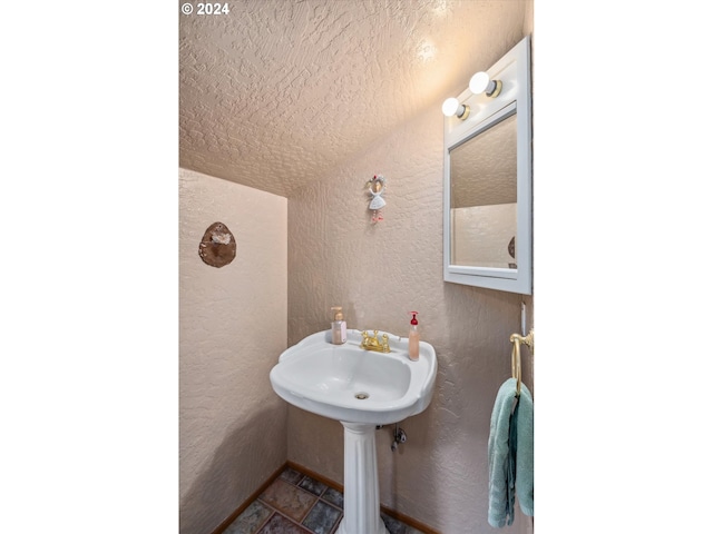 bathroom with a textured wall and a textured ceiling