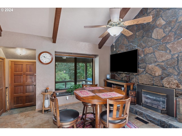 dining area with ceiling fan, a fireplace, stone finish floor, vaulted ceiling with beams, and visible vents