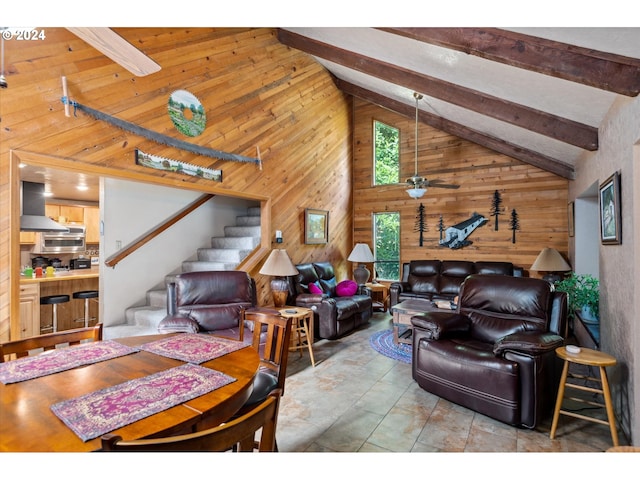 living room with wooden walls, high vaulted ceiling, beam ceiling, and stairway