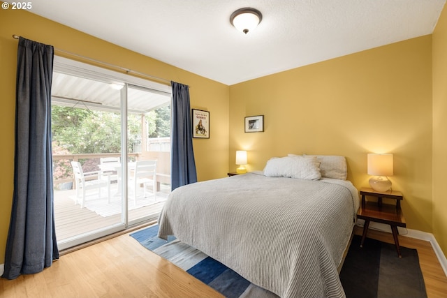 bedroom featuring access to exterior, wood finished floors, and baseboards