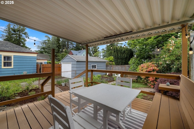 deck featuring outdoor dining space, a fenced backyard, and an outbuilding