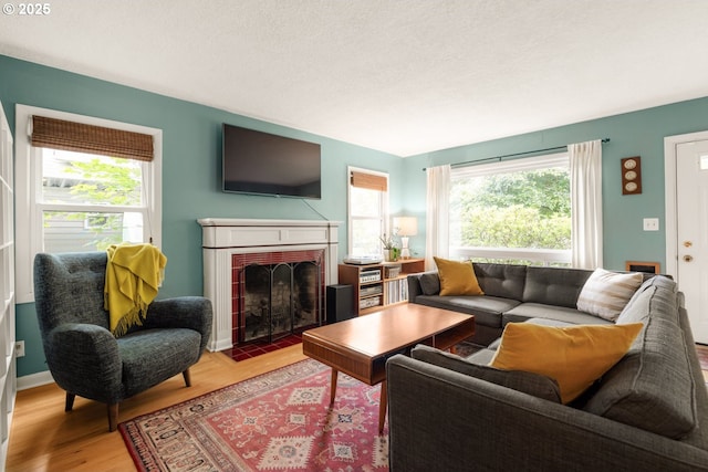 living area featuring plenty of natural light, a fireplace with flush hearth, wood finished floors, and baseboards