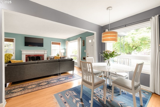 dining room featuring wood finished floors, healthy amount of natural light, and a brick fireplace