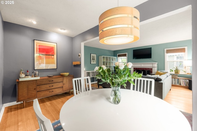 dining area with wood finished floors, a brick fireplace, and baseboards