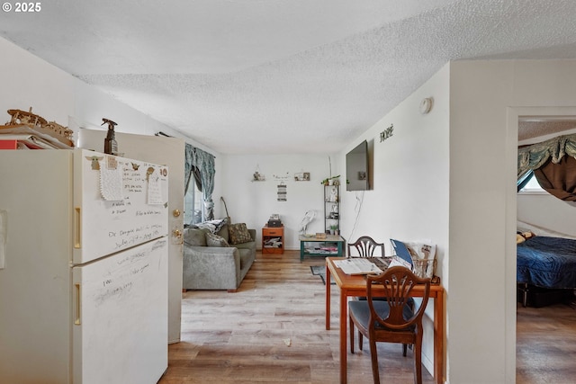dining area with a textured ceiling, wood finished floors, and healthy amount of natural light