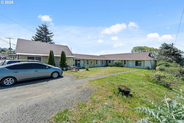 ranch-style house featuring a front lawn and gravel driveway
