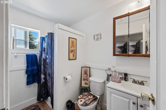 bathroom featuring curtained shower, toilet, vanity, baseboards, and wood finished floors
