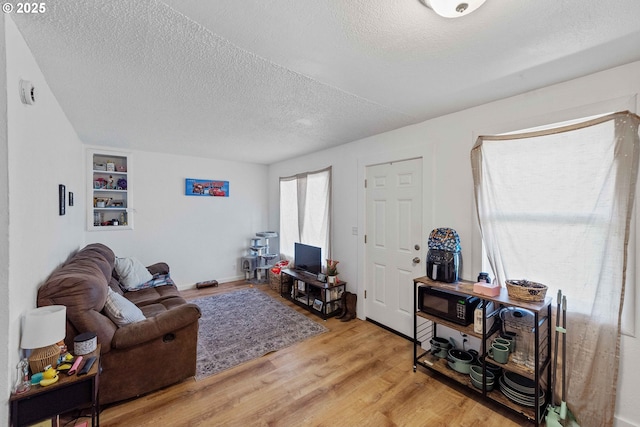 living room with a textured ceiling, wood finished floors, and built in shelves