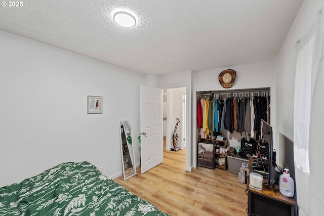 bedroom with wood finished floors, a textured ceiling, and a closet