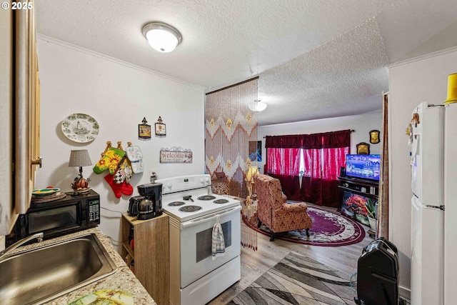 kitchen featuring white appliances, a sink, wood finished floors, and a textured ceiling