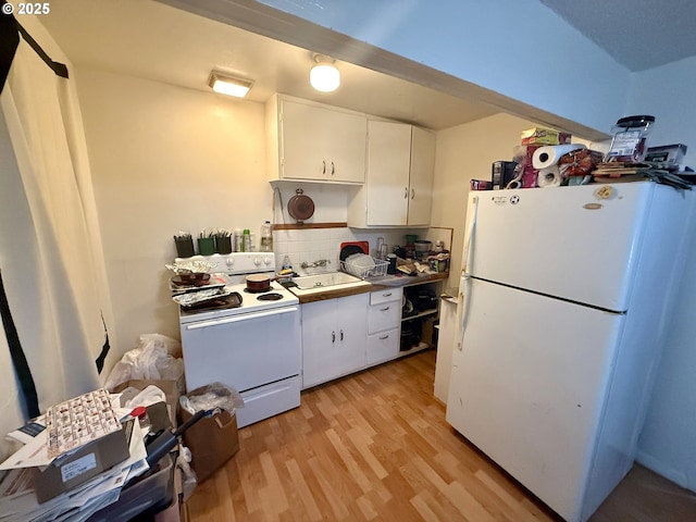 kitchen with white appliances, light wood-style floors, white cabinetry, a sink, and backsplash