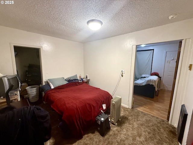 bedroom with carpet, a textured ceiling, and radiator
