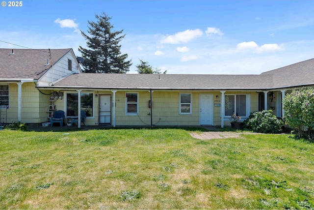 back of house with a lawn and roof with shingles
