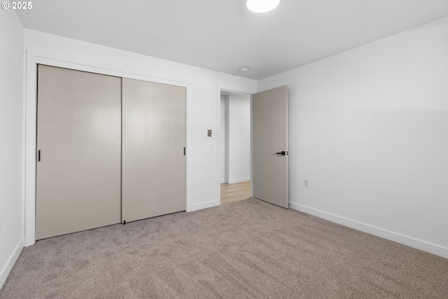 unfurnished bedroom featuring a closet and light carpet