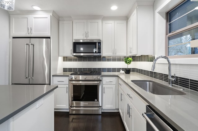 kitchen with dark hardwood / wood-style floors, sink, backsplash, white cabinets, and stainless steel appliances