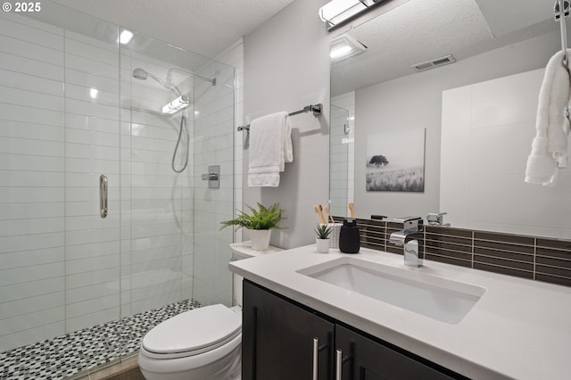 bathroom featuring tasteful backsplash, vanity, an enclosed shower, toilet, and a textured ceiling